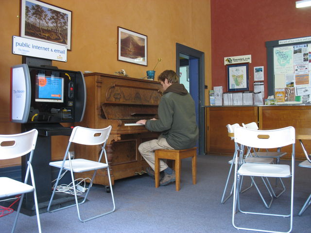 Hugues jouant du piano dans le salon-salle à manger de l'auberge Launceston Backpackers, où nous logeons ; à gauche, une borne web tournant sous GNU/Linux IMG_3333.JPG
